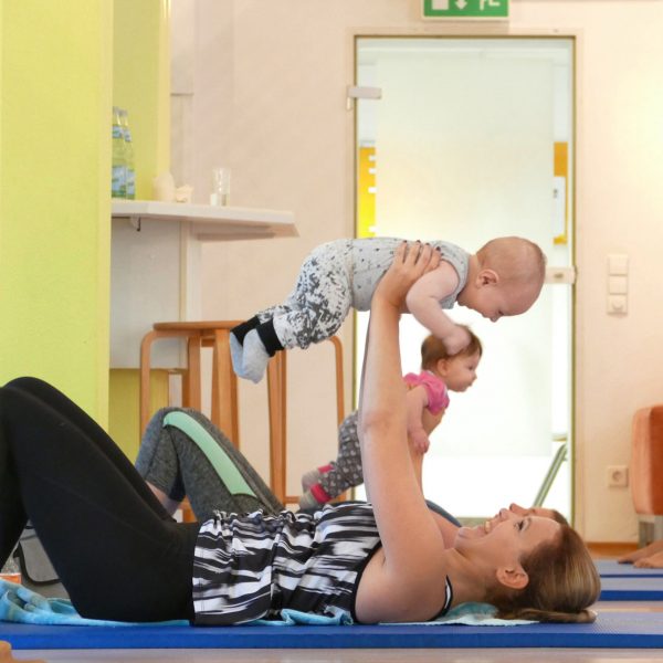 Eine Mutter turnt mit Ihrem Baby bei Mama & Baby AKTIV in der Elternschule Pforzheim